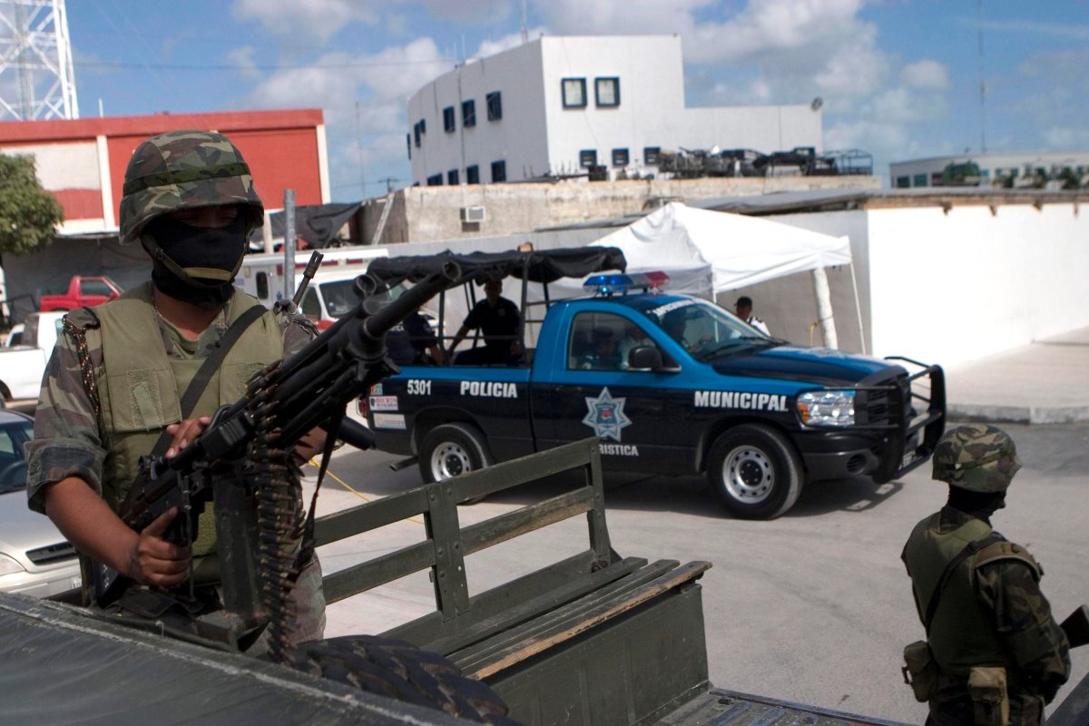FILE - A soldier stands atop an armored vehicle outside a police station in Cancun, Mexico. Eight bodies were found recently in the resort city.