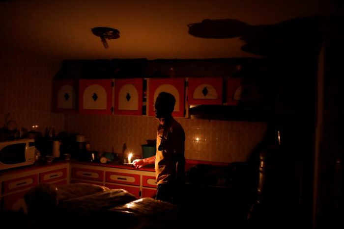 Americo Fernandez uses a candle to illuminate the kitchen at his home during a blackout in Maracaibo, July 25, 2018.