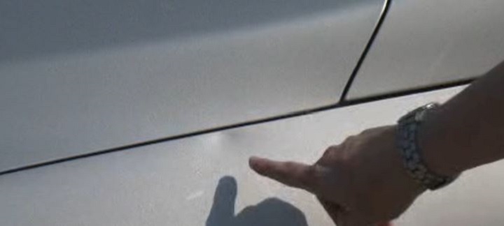 Deirdre Rowland points to the dent on her car after a stray baseball hit it.