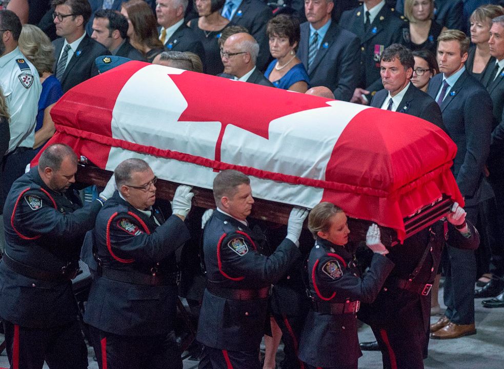 Intergovernmental Affairs Minister Dominic Leblanc and New Brunswick Premier Brian Gallant, right, look on as members of the Fredericton Police Force carry the casket for Const. Sara Burns at the regimental funeral for burns and Const. Robb Costello, killed in the line of duty, in Fredericton on Saturday, Aug. 18, 2018. The two city police officers were among four people who died in a shooting in a residential area on the city’s north side. THE CANADIAN PRESS/Andrew Vaughan