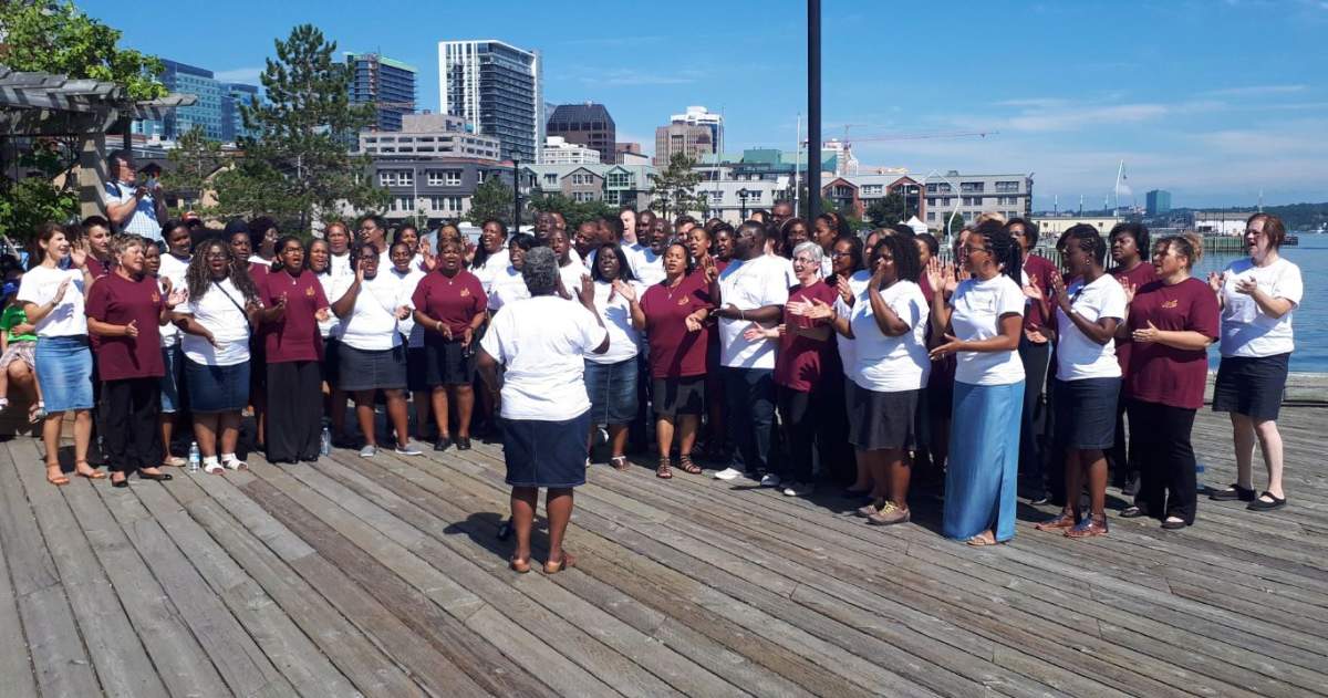 Karen Burke (foreground), director of Toronto Mass Choir, and singers from the Nova Scotia Mass Choir and the Toronto Mass Choir, are shown in Halifax, Saturday, Aug.4, 2018 Two award-winning Canadian gospel choirs wowed unsuspecting pedestrians on a busy waterfront Saturday morning with an impromptu performance. 
