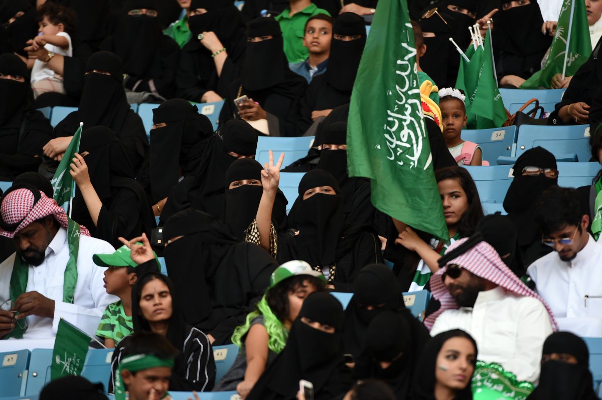 A Saudi woman flashes the victory gesture next to a girl carrying the national flag, as they sit with other families in a stadium to attend an event in the capital Riyadh on September 23, 2017 commemorating the anniversary of the founding of the kingdom.