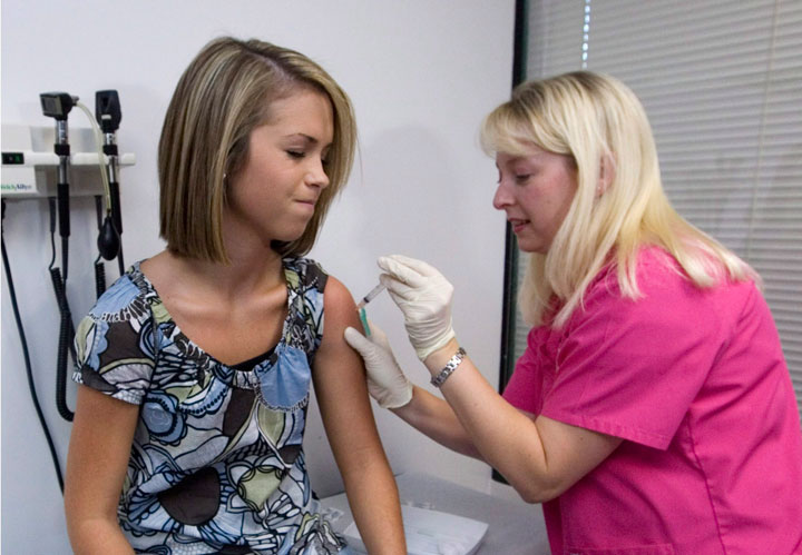 Lauren Fant, left, winces as she has her third and final application of the Human Papillomavirus (HPV) vaccine administered by nurse Stephanie Pearson at a doctor's office in Marietta, Ga. 