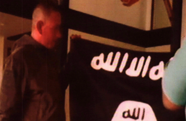 Army Sgt. 1st Class Ikaika Kang holds an Islamic State group flag after allegedly pledging allegiance to the group at a house in Honolulu, Hawaii on July 13, 2017.