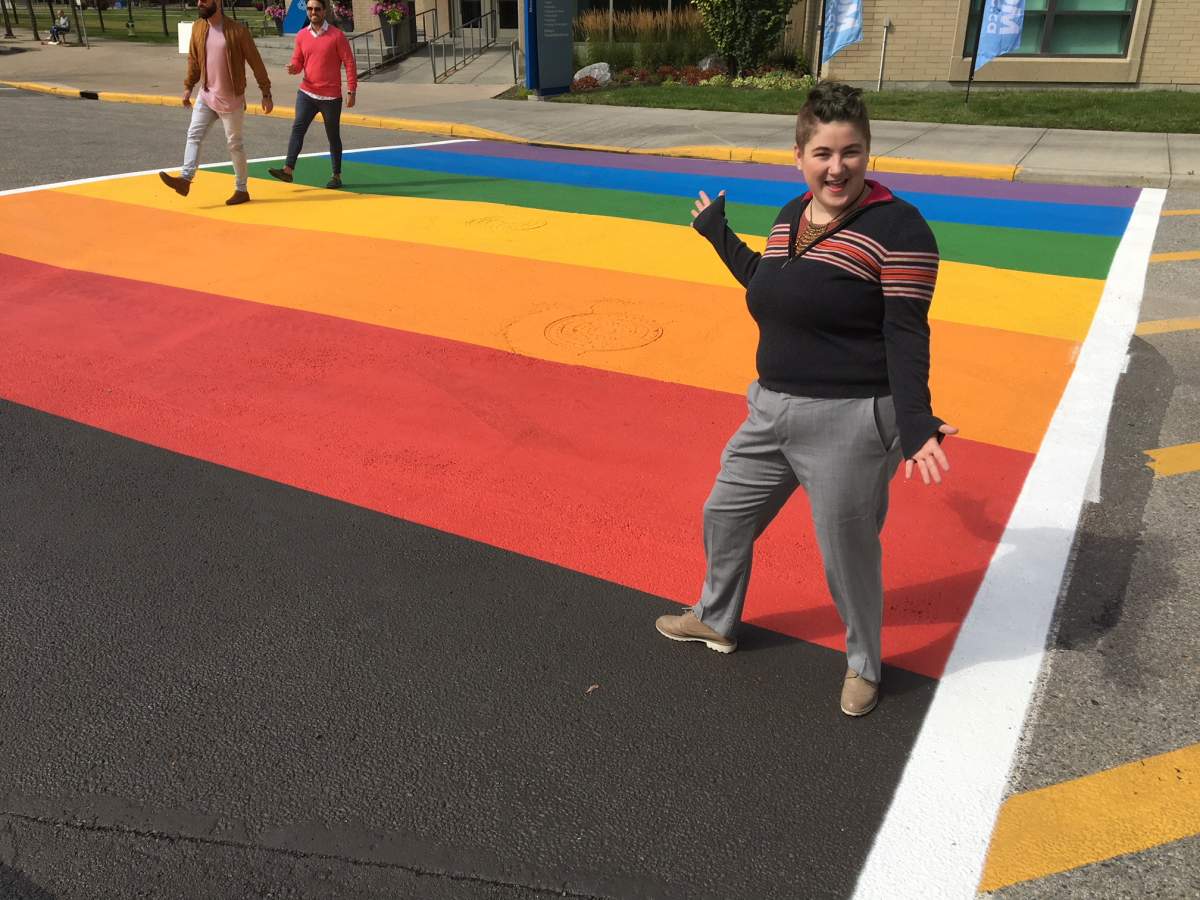 MRU student Eddy Robinson stands on the new, permanent rainbow crosswalk on the campus. 
