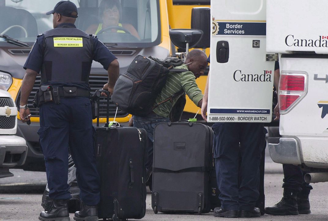 A second federal probe is underway in Prince Edward Island alleging hundreds of people gained permanent residency in Canada by using local addresses where they didn't live, under a provincial business immigration system that's faced criticism for loose oversight. A man removes his belongings from a CBSA truck at a processing centre for asylum seekers at the Canada-United States border in Lacolle, Que. Thursday, August 10, 2017. 