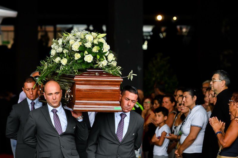 Pallbearers carry a coffin during a funeral service for some of the victims of a collapsed highway bridge, in Genoa’s exhibition center Fiera di Genova, Italy, Saturday, Aug. 18, 2018. Saturday has been declared a national day of mourning in Italy and includes a state funeral at the industrial port city’s fair grounds for those who plunged to their deaths as the 45-meter (150-foot) tall Morandi Bridge gave way Tuesday.