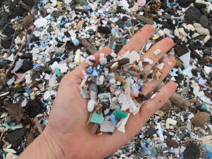 Sarah-Jeanne Royer holds a handful of degraded plastic bits on a beach in Hawaii.