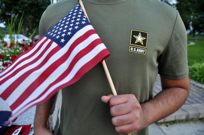 In this July 3, 2018 file photo, a Pakistani recruit, 22, who was recently discharged from the U.S. Army, holds an American flag as he poses for a picture.