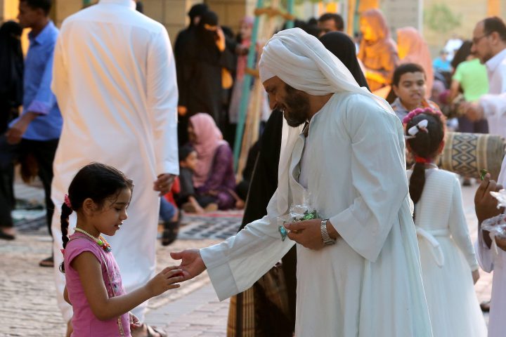 A man distributing sweets to children after Eid al-Adha prayer at King Abdul Aziz Mosque, Riyadh, Saudi Arabia, 21 August 2018.