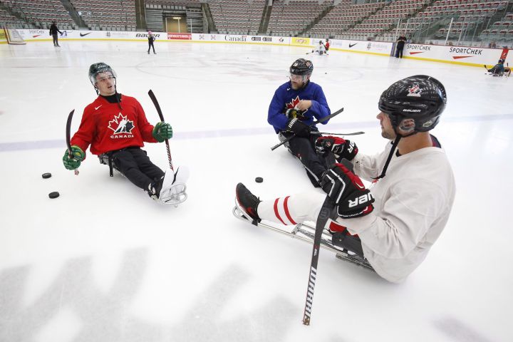 Ryan Straschnitzki, left to right, talks to former Calgary Flames' Brian McGrattan and his mentor Chris Cedarstrand on the ice as he practices his sledge hockey skills in Calgary on Tuesday, August 7, 2018. Straschnitzki was injured in the Humboldt Broncos bus crash. 
