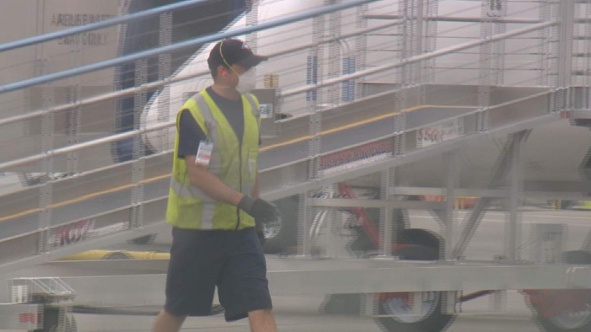 An employee at YYC Calgary International Airport wears a face mask as smoke from wildfires in B.C. enveloped the city on Wednesday.