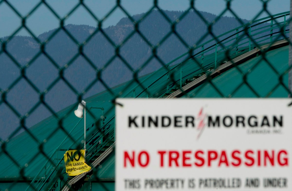 A sign left by Greenpeace activists is seen hanging on the staircase to a oil storage container at the Kinder Morgan facility in Burrard Inlet in Burnaby, B.C. Wednesday, Oct. 16, 2013. 