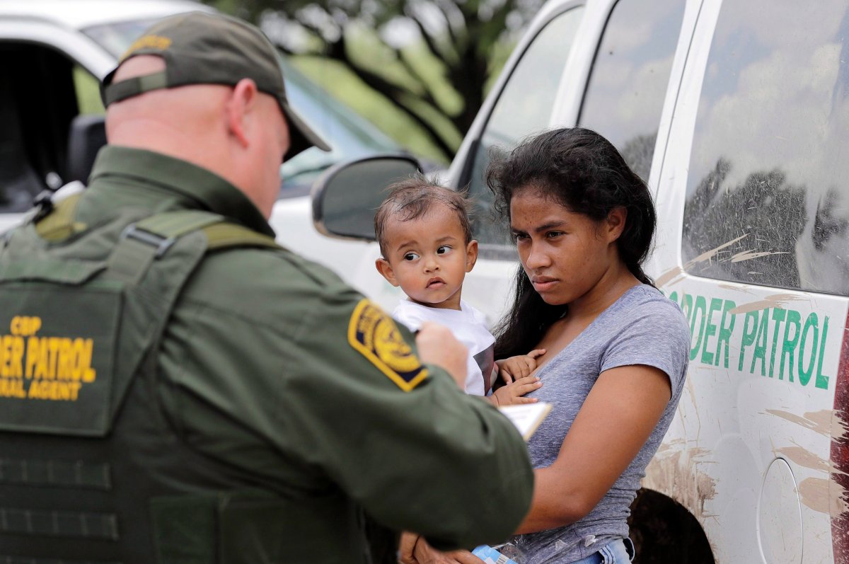 In this Monday, June 25, 2018 file photo, a mother migrating from Honduras holds her 1-year-old child as surrendering to U.S. Border Patrol agents after illegally crossing the border, near McAllen, Texas. 