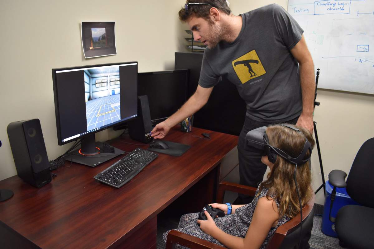 Andrew Vierich, a software developer at the University of Guelph, looks on as Ruby Corbett learns how to safely cross streets using a virtual reality program Vierich helped design in this undated handout photo. 