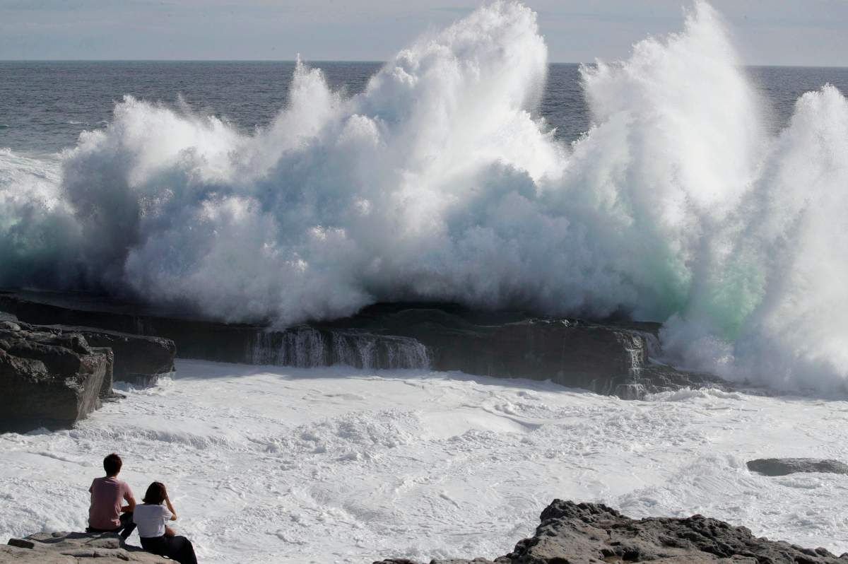 A couple watches waves hitting a coast of Shirahara town, Wakayama prefecture, central Japan, Monday, Sept. 3, 2018.