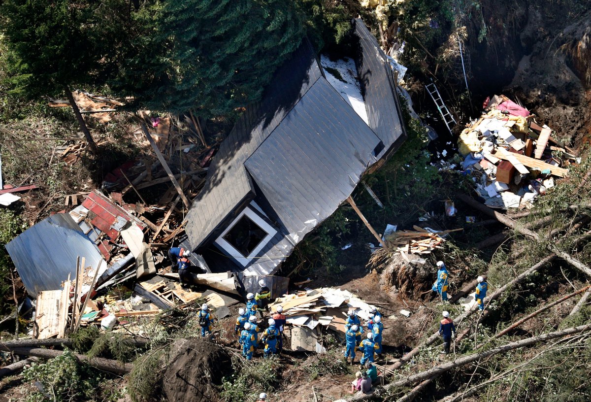 Police search missing persons around houses destroyed by a landslide after an earthquake in Atsuma town, Hokkaido, northern Japan, Thursday, Sept. 6, 2018.