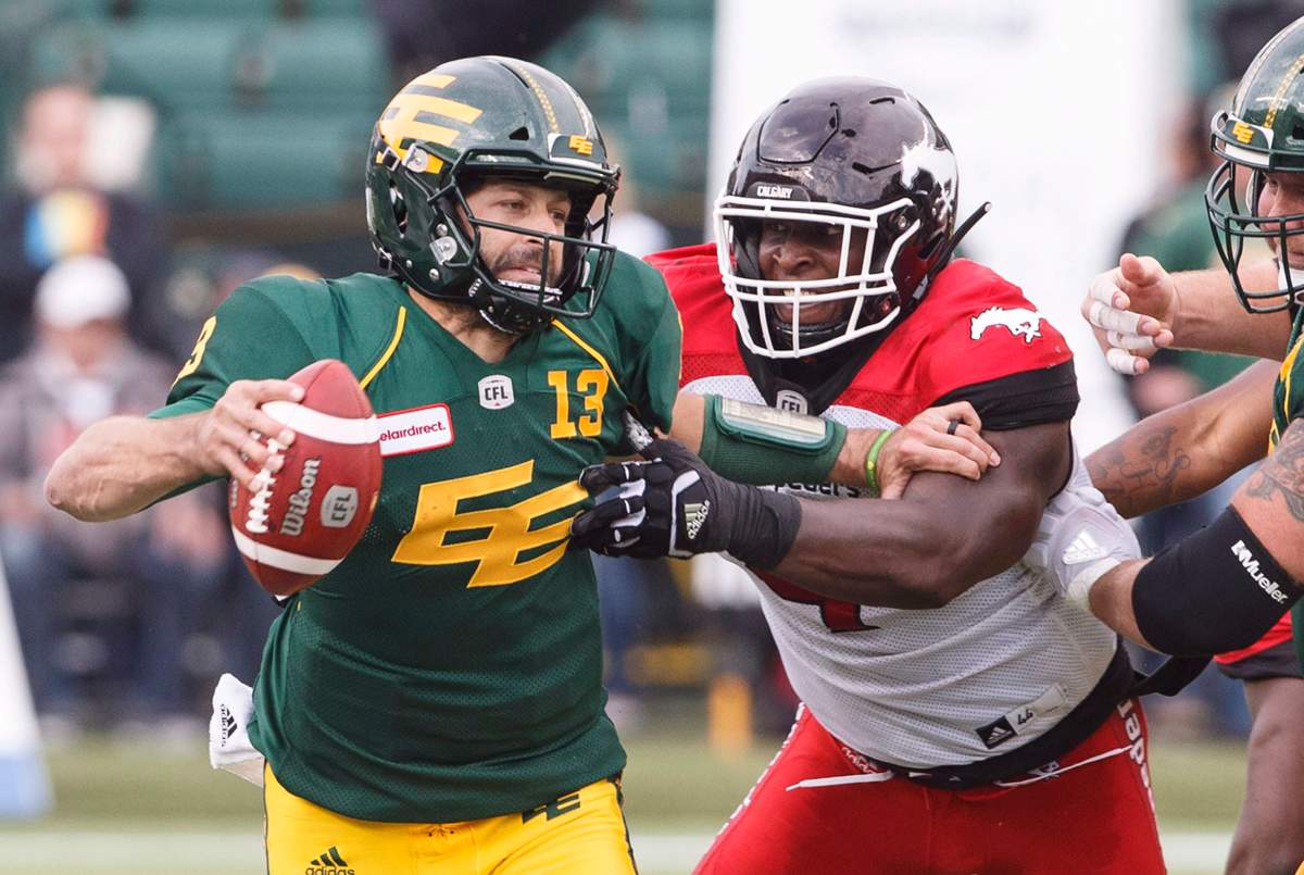 Calgary Stampeders Micah Johnson (4) grabs Edmonton Eskimos quarterback Mike Reilly (13) during first half CFL action in Edmonton, Alta., on Saturday September 8, 2018. THE CANADIAN PRESS/Jason Franson.