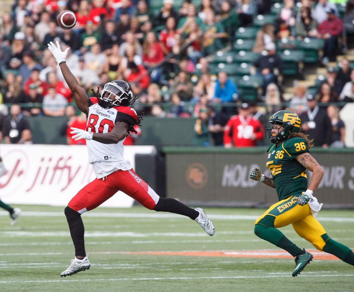 Calgary Stampeders Marken Michel (80) reaches for the ball as he is chased by Edmonton Eskimos Aaron Grymes (36) during first half CFL action in Edmonton, Alta., on Saturday September 8, 2018. THE CANADIAN PRESS/Jason Franson.
