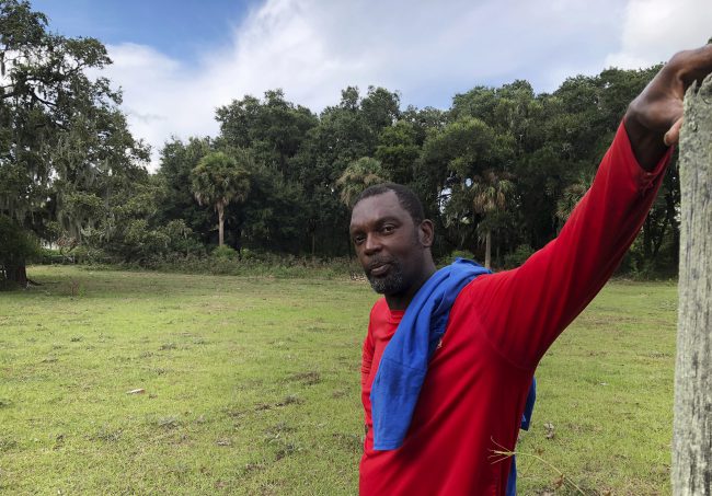 John Brown stands behind a fence for his cows outside his home on St. Helena Island, S.C., Sept. 11, 2018.