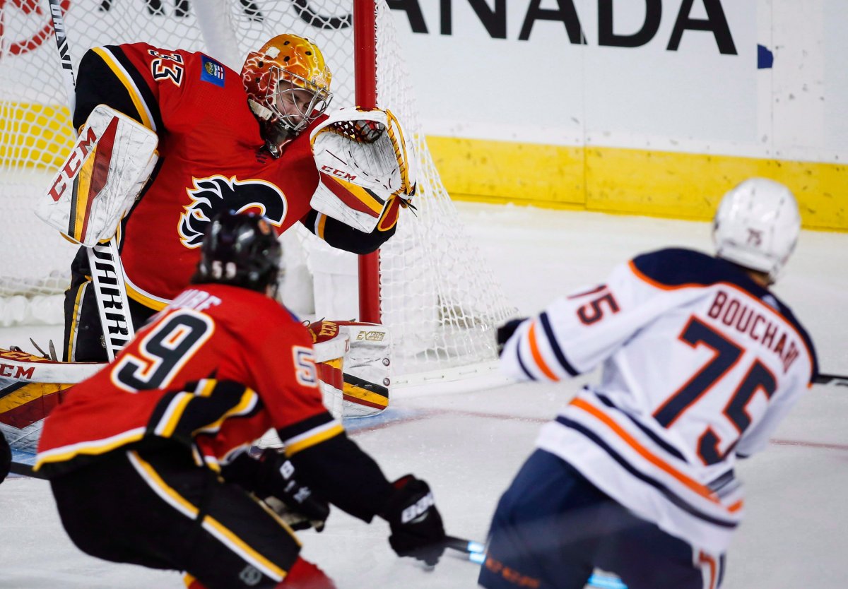 Edmonton Oilers' Evan Bouchard, right, scores on Calgary Flames goalie David Rittich, from the Czech Republic, during first period preseason NHL hockey action in Calgary, Monday, Sept. 17, 2018. THE CANADIAN PRESS/Jeff McIntosh.