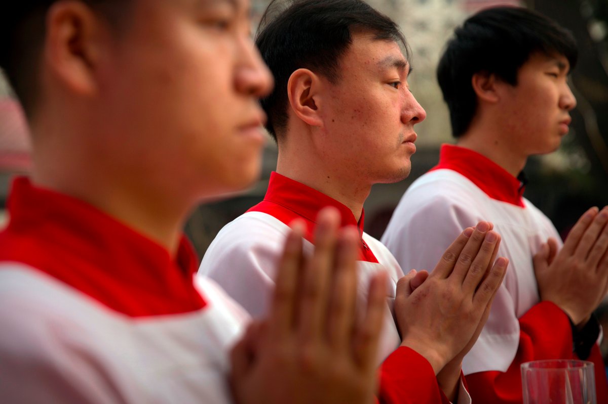 FILE - In this Saturday, March 31, 2018, file photo, Chinese acolytes pray during a Holy Saturday Mass on the evening before Easter at the Cathedral of the Immaculate Conception, a government-sanctioned Catholic church in Beijing. 