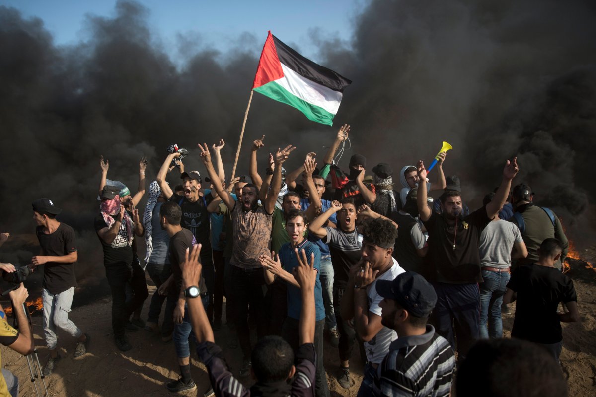 Palestinians chant slogans in front of black smoke rising from burning tires during a protest at the Gaza Strip's border with Israel, Friday, Sept. 28, 2018. 