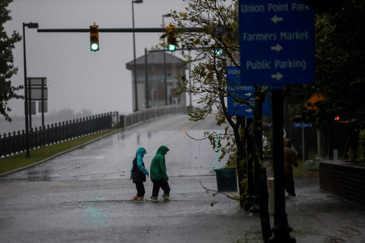 People walk on a local street as water from Neuse River starts flooding houses upon Hurricane Florence coming ashore in New Bern, North Carolina, U.S., September 13, 2018.