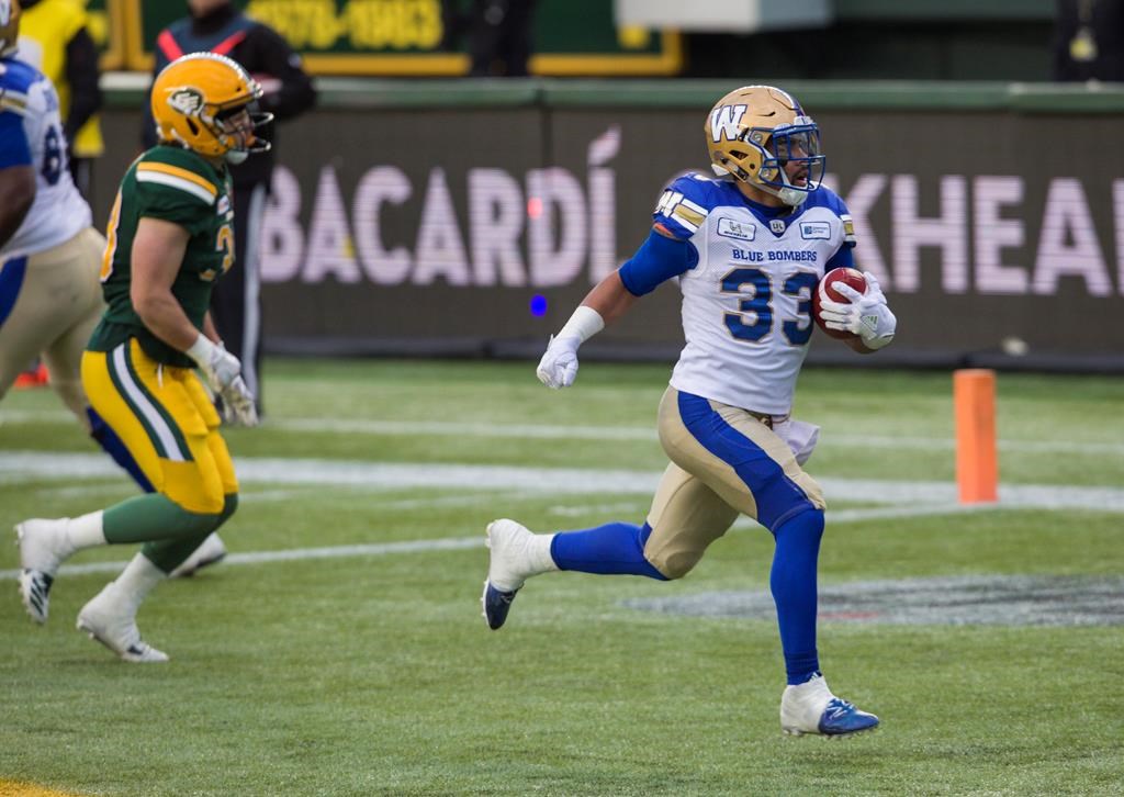 Winnipeg Blue Bombers' Andrew Harris (33) runs in a touchdown ahead of Edmonton Eskimos' Adam Konar (38) during first half CFL action in Edmonton, Alta., on Saturday September 29, 2018. THE CANADIAN PRESS/Amber Bracken.