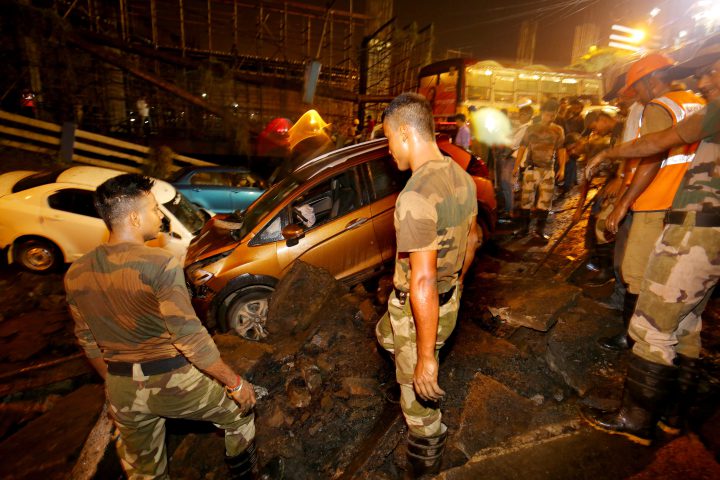 People gather while National Disaster Response Force (NDRF) and Indian army personnel work at the site of a collapsed bridge in Kolkata, Eastern India, on Sept. 4, 2018.