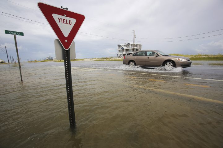 A car drives through a road as it slowly begins to flood as Tropical Storm Gordon approaches on Tuesday, Sept. 4, 2018, in Dauphin Island, Ala. 