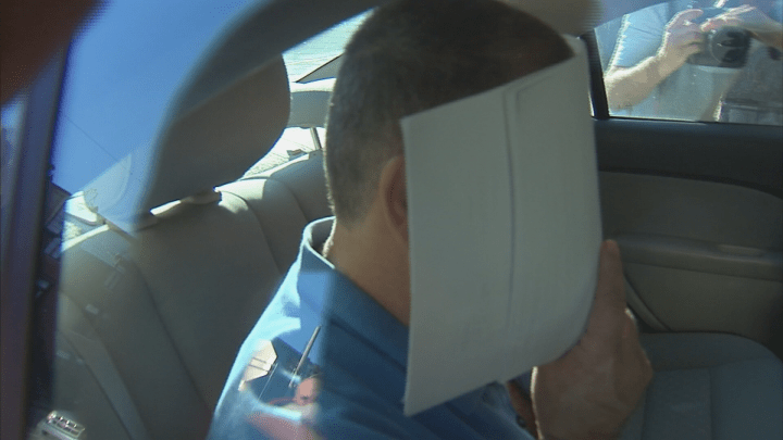 Paul Zaidan hides his face from cameras following his arrest Tuesday, Sept. 4, 2018.