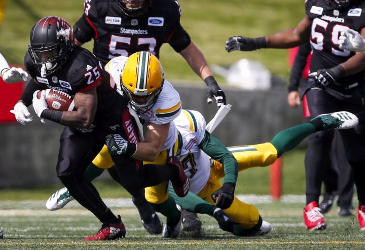 Edmonton Eskimos' players tackle Calgary Stampeders' Don Jackson during first half CFL football action in Calgary, Monday, Sept. 3, 2018.