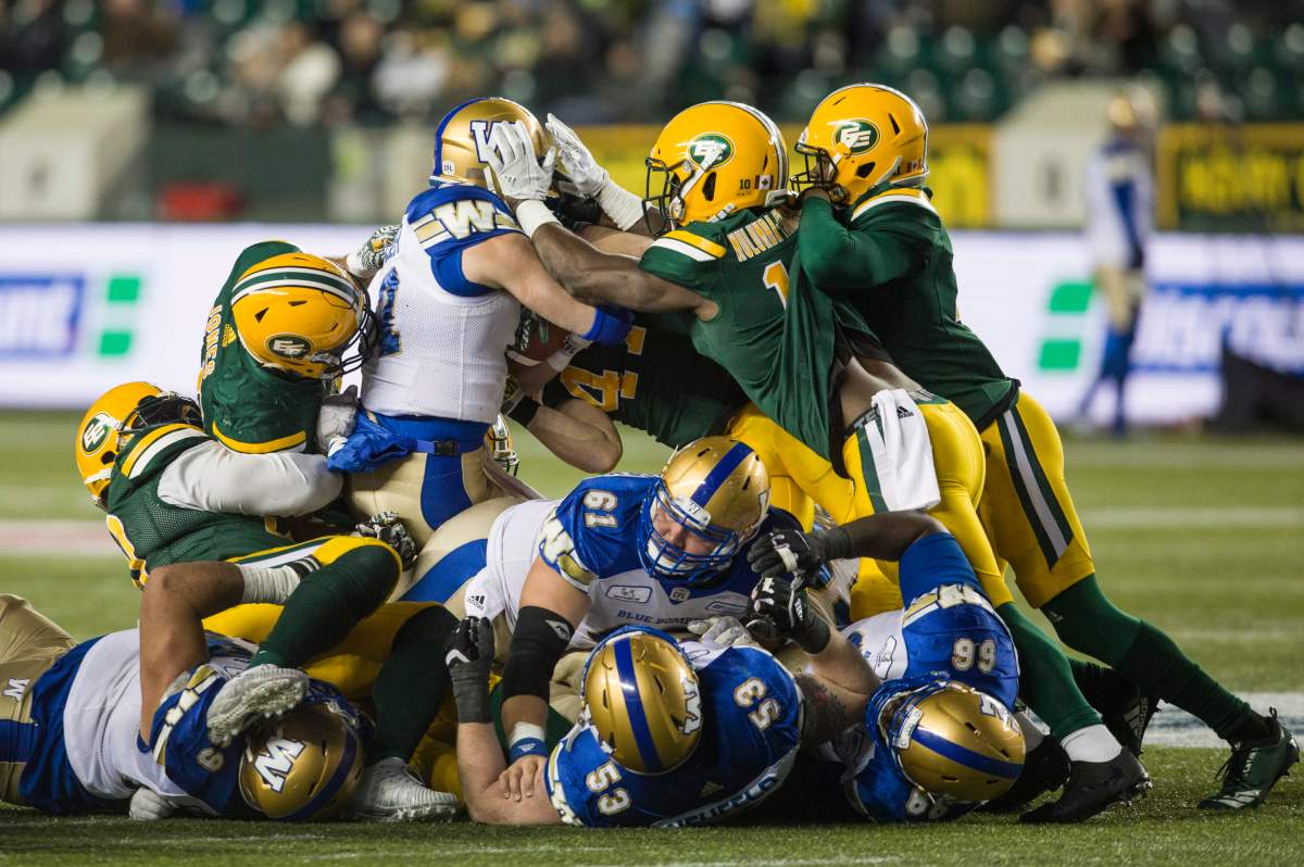 Winnipeg Blue Bombers quarterback Chris Streveler (17) carries the ball into a pile up with Edmonton Eskimos Monshadrik Hunter (41), Christophe Mulumba-Tshimanga (10), Nate Behar (11), Korey Jones (45) and Blue Bomber Sukh Chungh (69), Patrick Neufeld (53), Matthias Goossen (61), Stanley Bryant (66) during second half CFL action in Edmonton, Alta., on Saturday September 29, 2018.