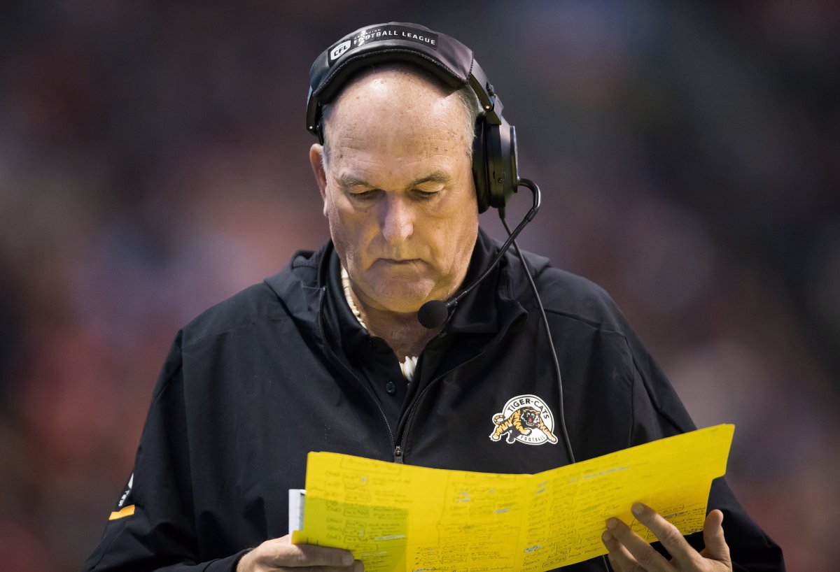 Hamilton Tiger-Cats head coach June Jones looks at a list of plays while standing on the sideline during the first half of a CFL football game against the B.C. Lions in Vancouver, on Saturday September 22, 2018.