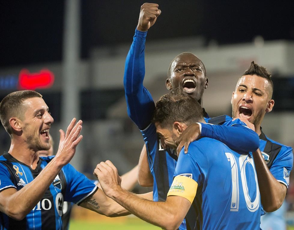 In this file photo, Montreal Impact's Micheal Azira, center, celebrates with teammates.