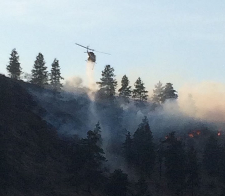 A helicopter buckets water onto the Okanagan Falls wildfire on Friday afternoon.