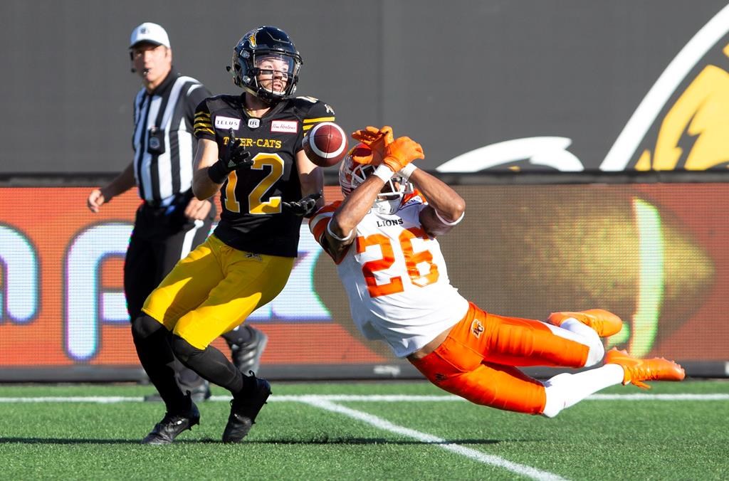 The ball slips through the hands of BC Lions defensive back Anthony Orange (26) straight into the hands of Hamilton Tiger-Cats wide receiver Mike Jones (12) during first half CFL Football game action in Hamilton, Ont. on Saturday, September 29, 2018.