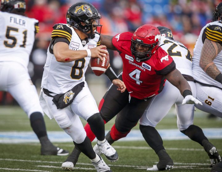 Hamilton Tiger-Cats quarterback Jeremiah Masoli, left, runs from Calgary Stampeders' Micah Johnson during second half CFL football action in Calgary, Saturday, June 16, 2018.