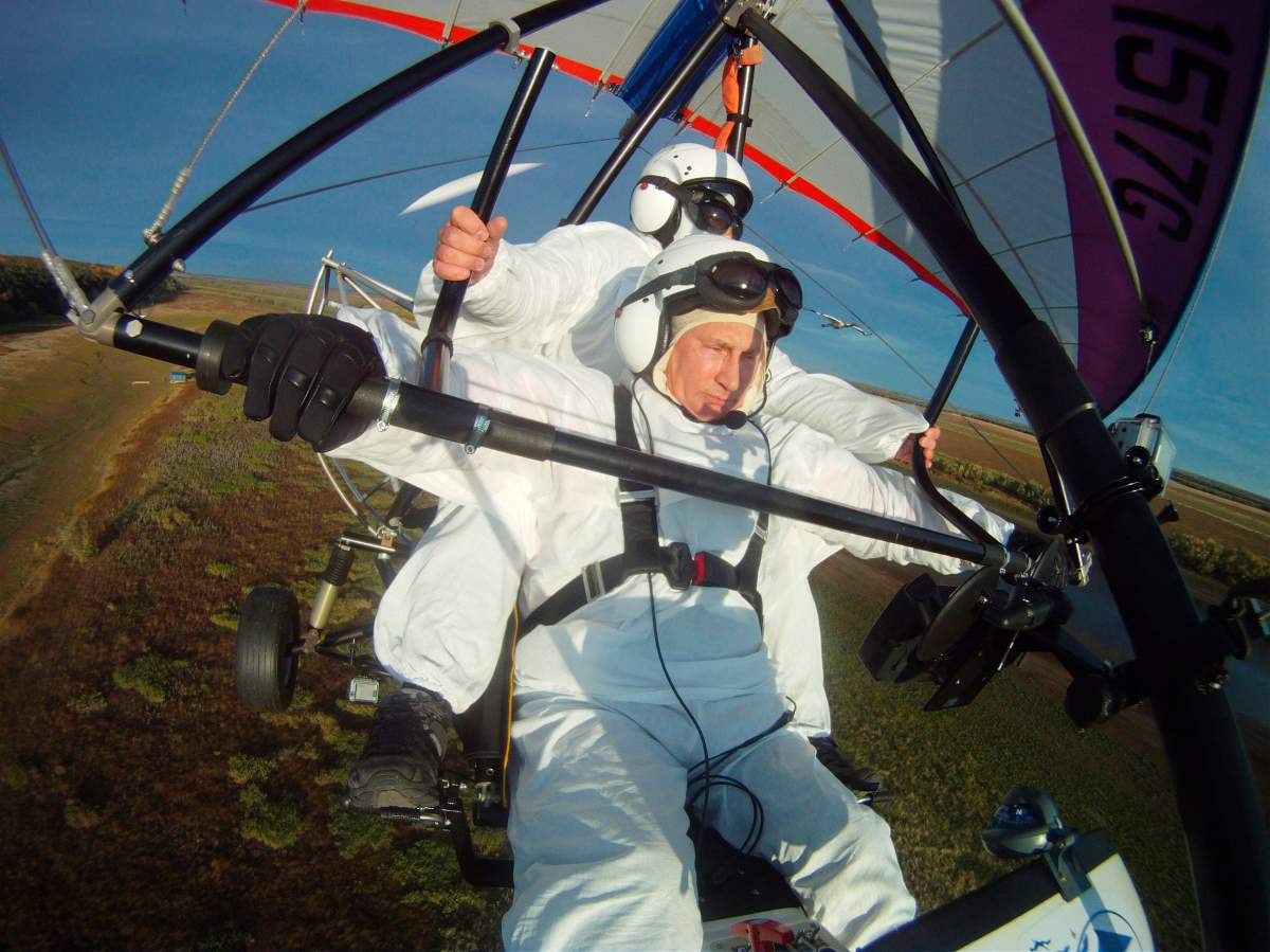 In this Sept. 5, 2012, file photo, Russian President Vladimir Putin, foreground, flies in a motorized hang glider alongside a Siberian white crane, on the Yamal Peninsula, in Russia. Putin has become alternately notorious and beloved for an array of adventurous stunts.