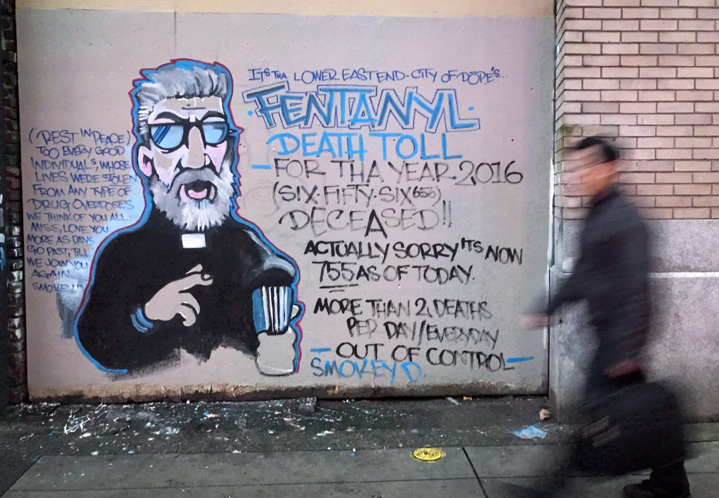 A man walks past a mural by street artist Smokey D. painted as a response to the fentanyl and opioid overdose crisis, in the Downtown Eastside of Vancouver, B.C., on Thursday, December 22, 2016. 