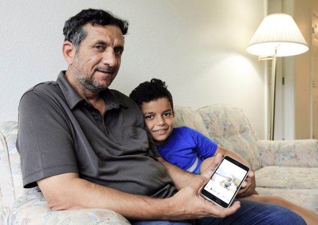 Hadi Mohammed sits with his 9 year old son Mohammed Ghaleb, as he displays a photo of his son as a baby in Baghdad, in their Lincoln, Neb. apartment, Sept. 29, 2018.