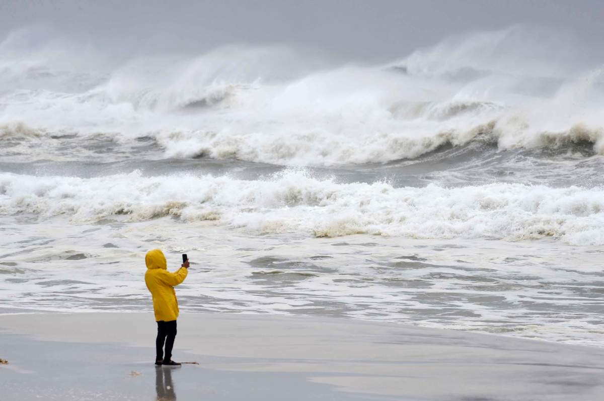 An unidentified person takes pictures of the surf and fishing pier on Okaloosa Island in Fort Walton Beach, Fla., on Wednesday, Oct. 10, 2018, as Hurricane Michael approaches the Florida Gulf Coast.