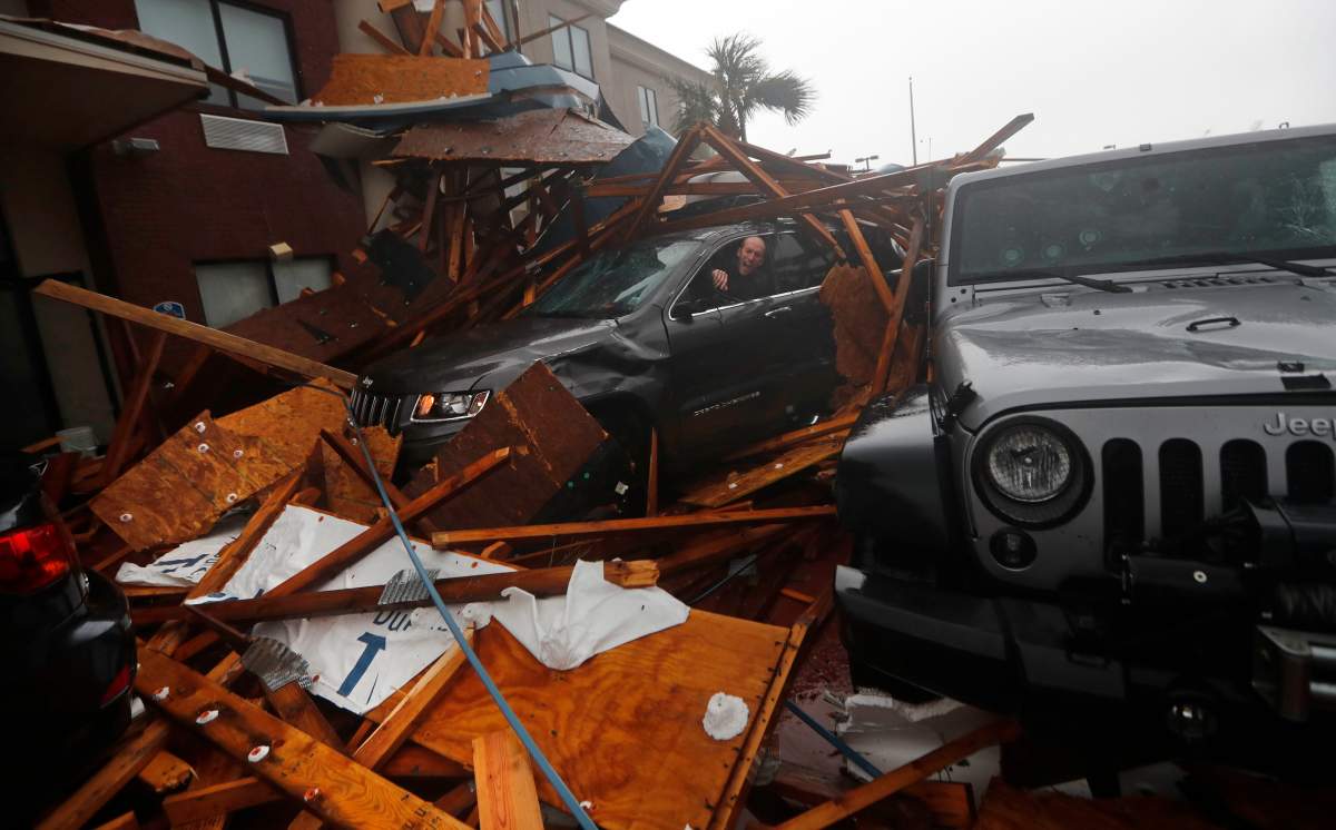 A storm chaser climbs into his vehicle during the eye of Hurricane Michael to retrieve equipment after a hotel canopy collapsed in Panama City Beach, Fla., Wednesday, Oct. 10, 2018.