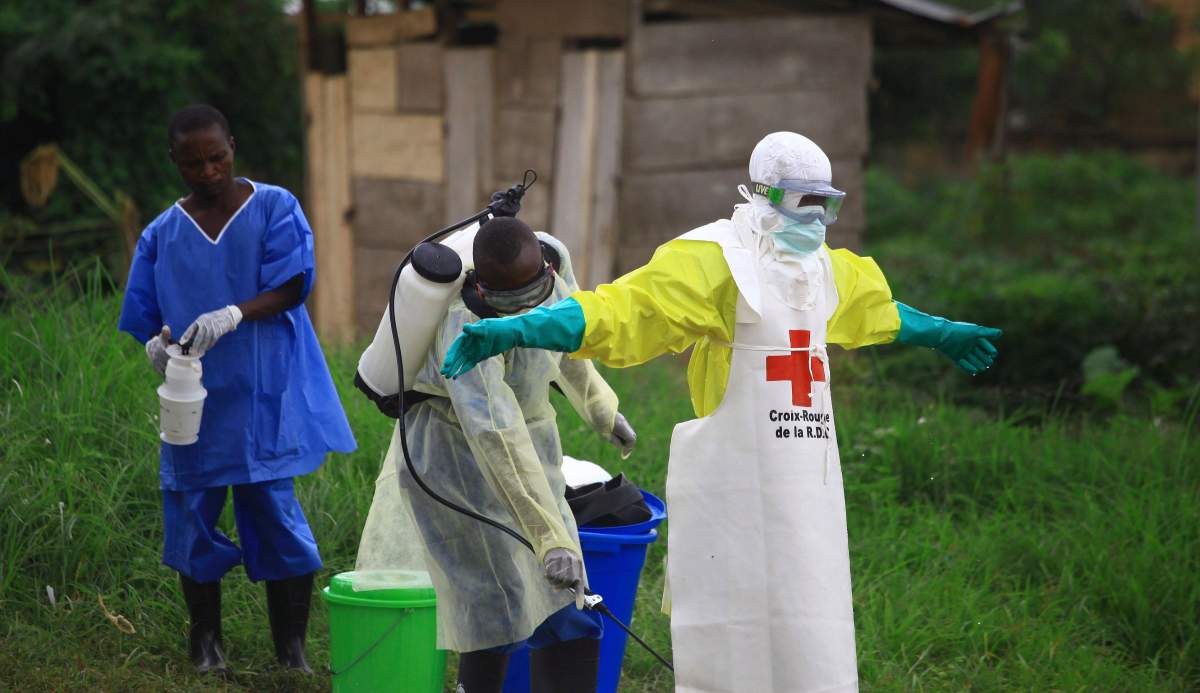 FILE - In this Sept. 9, 2018, file photo, a health worker sprays disinfectant on his colleague after working at an Ebola treatment center in Beni, Eastern Congo.