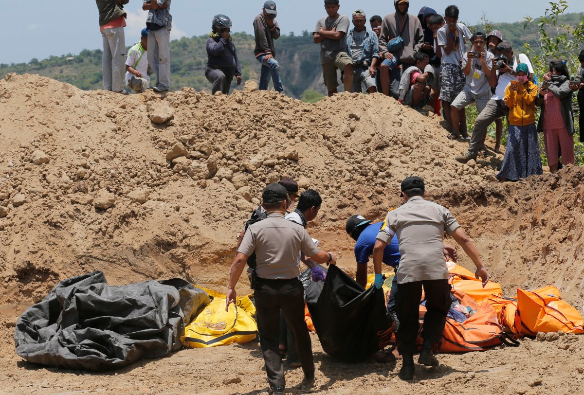  In this Monday, Oct. 12, 2018, file photo, rescue teams carry the bodies of victims to a mass grave following a major earthquake and tsunami in Palu, Central Sulawesi, Indonesia. 