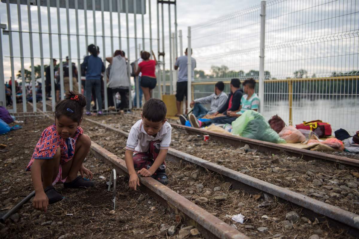 A couple of children from Honduras, part of a U.S.-bound caravan of migrants, play on the train tracks that cross the border between Guatemala and Mexico.