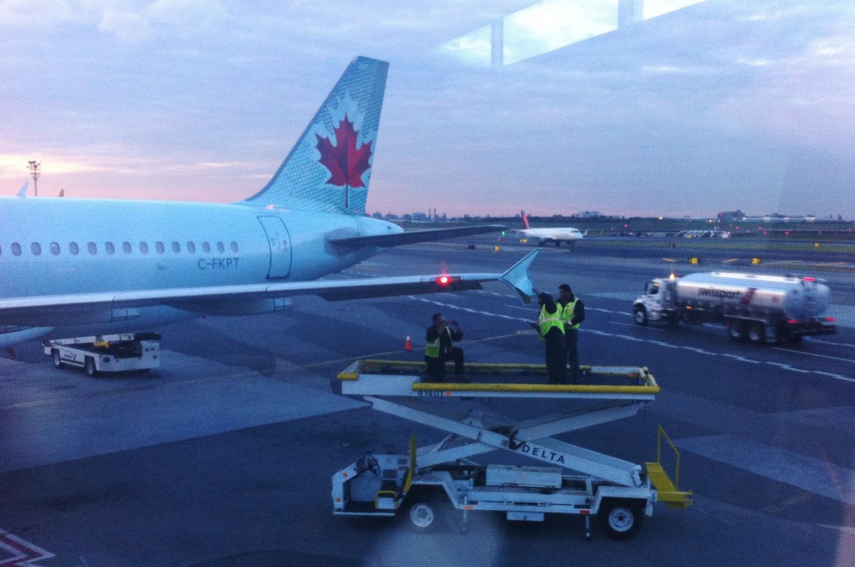 Runway crew members examine the wing tip of an Air Canada plane which arrived at LaGuardia Airport in New York on Monday, Oct. 22, 2018. An Air Canada flight that had just landed at New York's LaGuardia Airport late Monday afternoon was damaged as it sat on the taxiway by another passing plane. New York Port Authority spokesman Rudy King says the Air Canada jet was stationary on the taxiway when an American Airlines plane that was attempting to turn clipped its wing. 