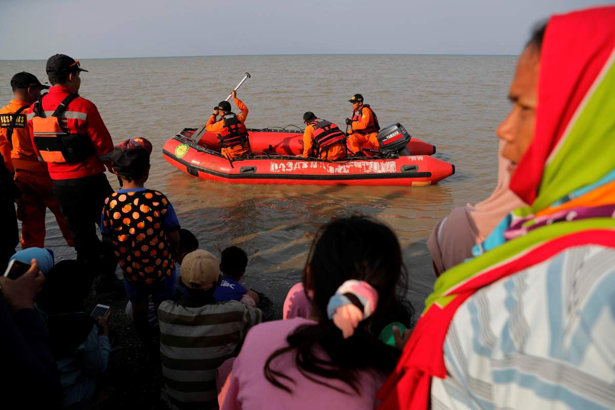 People watch rescue team members prepare the boat heading to the Lion Air, flight JT610, sea crash site off the coast of Karawang regency, West Java province, Indonesia, October 29, 2018. REUTERS/Beawiharta