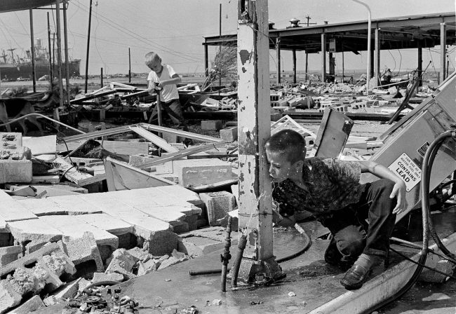 An 11-year-old boy drinks from a broken pipe amid the ruins of his father’s service station in Gulfport, Miss. in the aftermath of Hurricane Camille, Aug. 19, 1969,